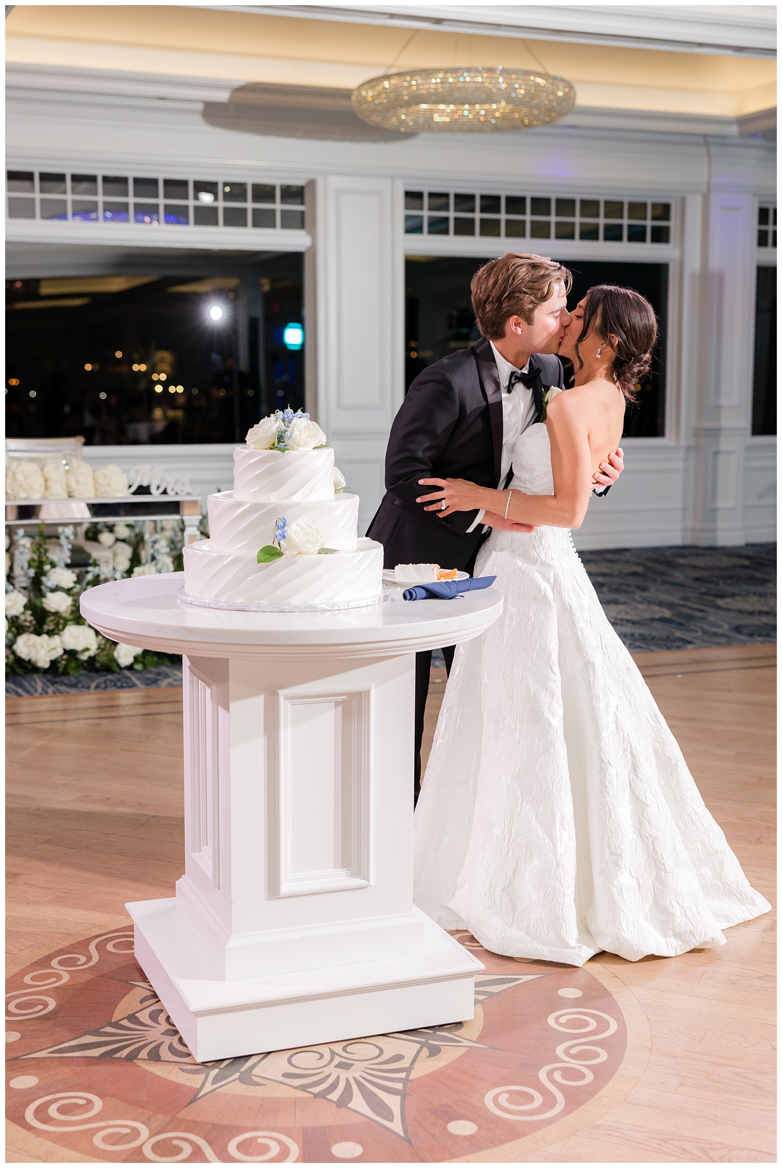 bride and groom kissing next to thewedding cake
