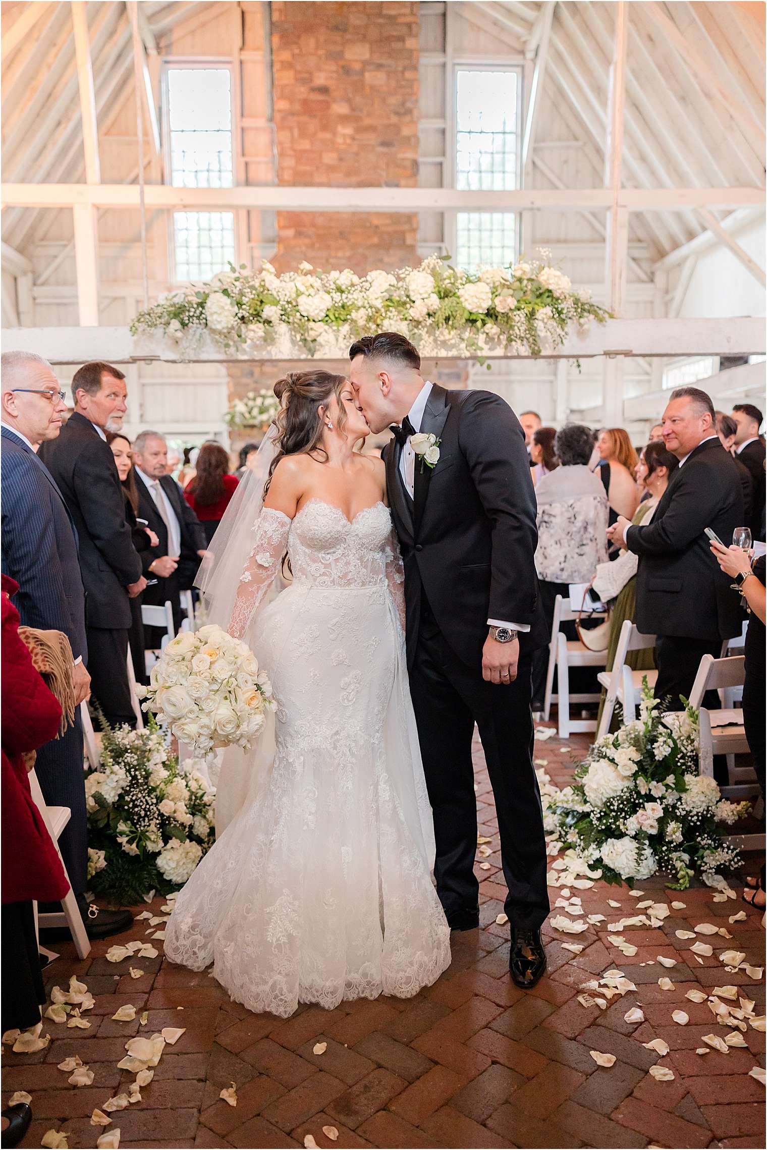 bride and groom kissing in aisle after wedding ceremony in the barn at Ashford Estate in Allentown NJ